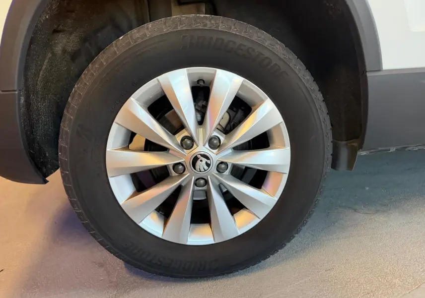 Gros plan sur la roue avant droite d’un Skoda Karoq blanc 2023 avec jante alliage et pneu Bridgestone.