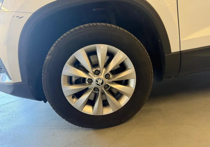 Gros plan sur la roue avant gauche du Skoda Karoq blanc 2023, mettant en valeur la jante alliage spécifique.