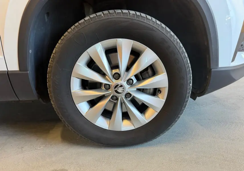 Gros plan sur la roue avant gauche du Skoda Karoq blanc 2023, mettant en valeur la jante alliage à dix branches.