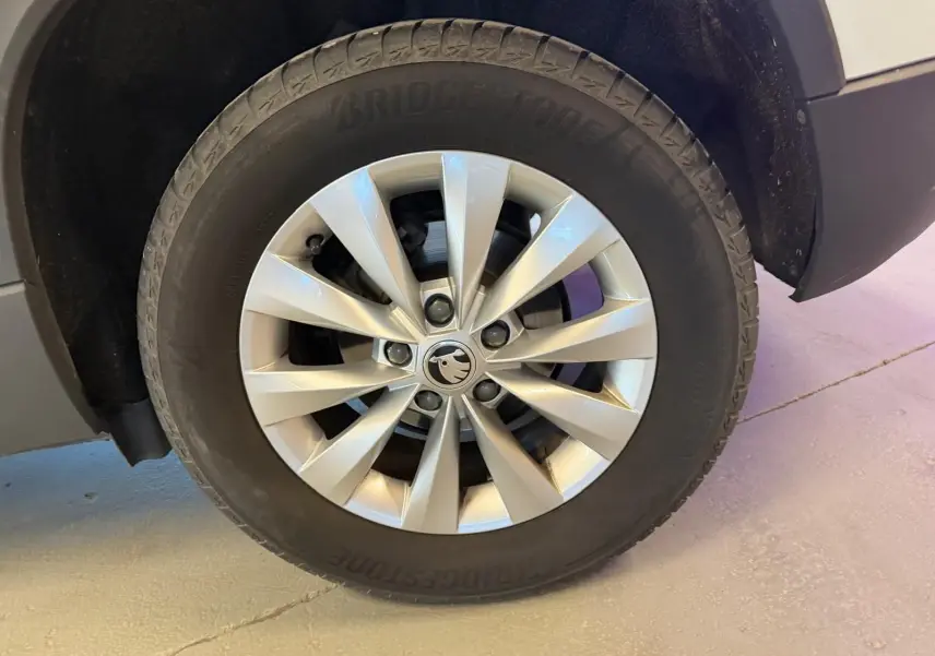 Gros plan sur la roue avant gauche du Skoda Karoq blanc 2023, avec jante alliage argentée et pneu Bridgestone.