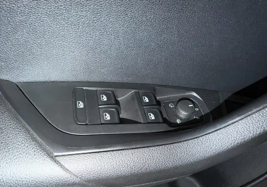 Gros plan sur les commandes des vitres et rétroviseurs côté conducteur du Skoda Karoq blanc 2023.