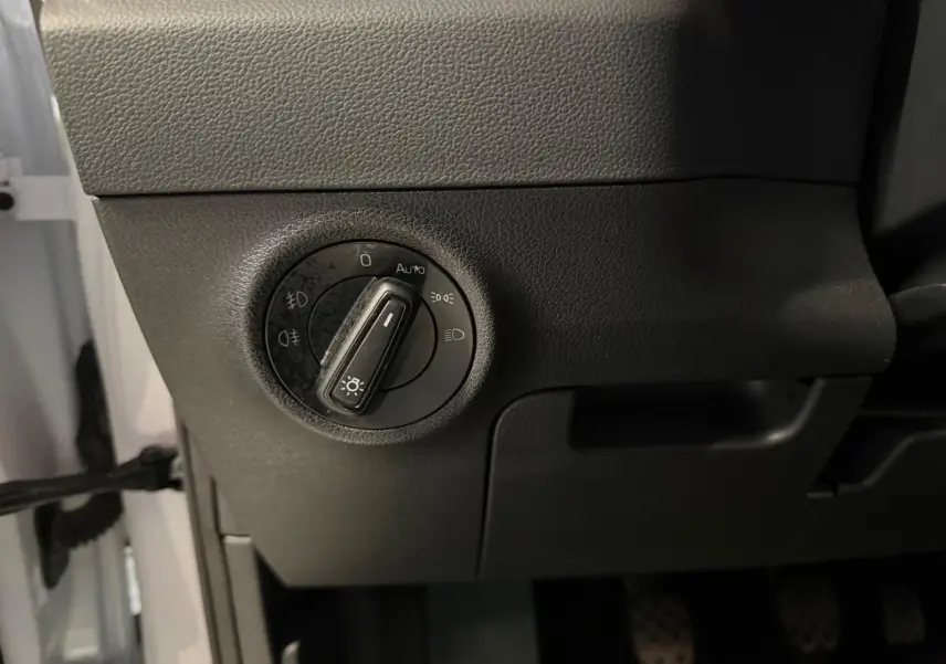 Détail du bouton de commande des phares sur la partie gauche du tableau de bord d’un Skoda Karoq blanc 2023.