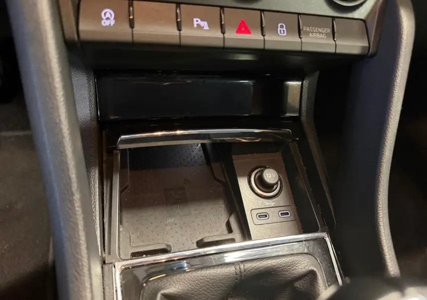 Gros plan intérieur sur la console centrale du Skoda Karoq blanc 2023, montrant prises USB, prise 12V et boutons de contrôle.