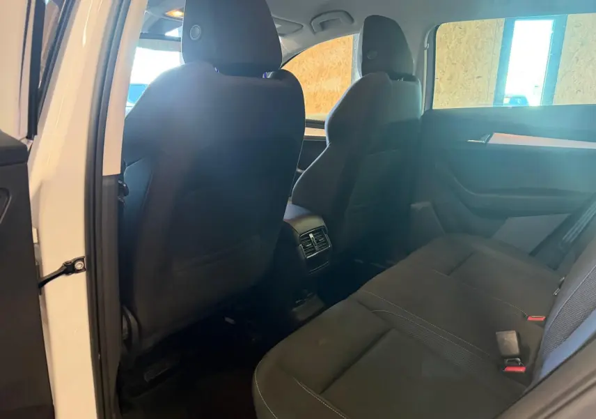 Vue intérieure arrière du Skoda Karoq blanc 2023, montrant les sièges noirs et les aérateurs centraux arrière.