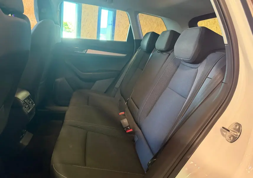 Vue intérieure côté droit sur les sièges arrière noirs du Skoda Karoq blanc 2023, porte arrière ouverte.