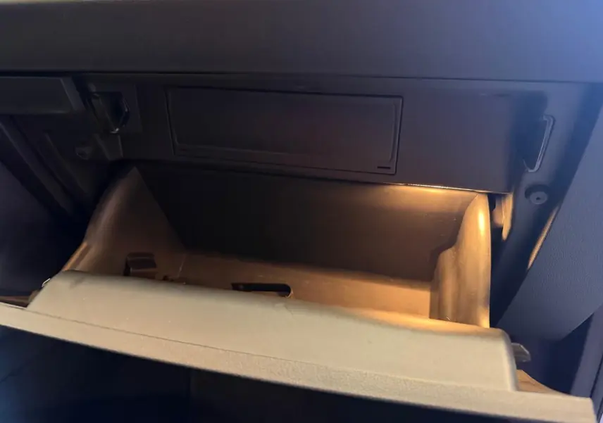 Vide-boîte à gants éclairé dans l’habitacle sombre d’un Skoda Karoq 1.5 TSI blanc, version Ambition 2023.