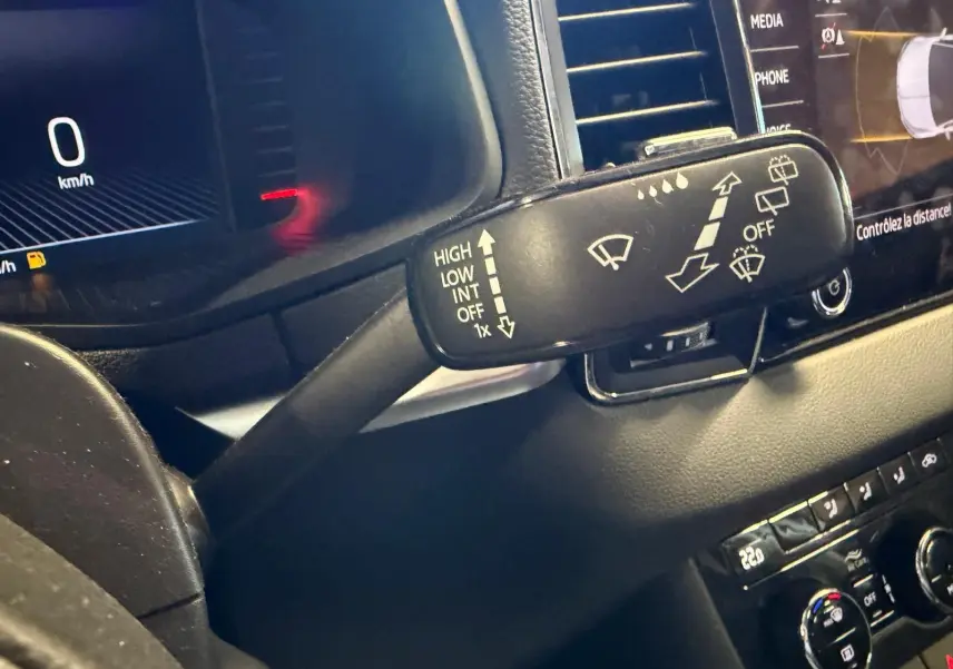 Gros plan sur la commande d’essuie-glace du tableau de bord noir du Skoda Karoq blanc 2023, version essence.