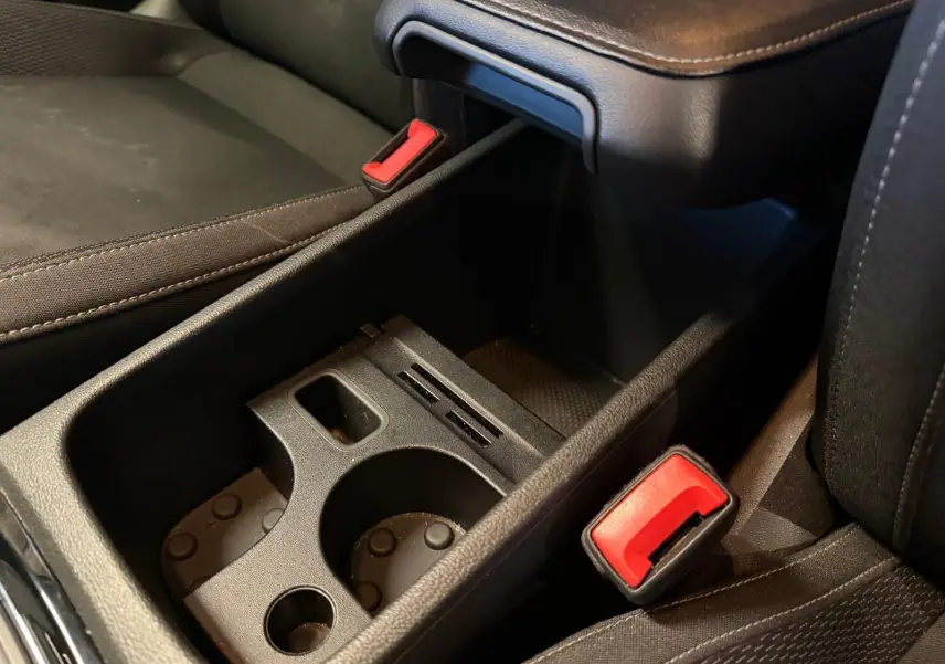 Gros plan sur la console centrale noire avec porte-gobelets et ceintures de sécurité rouges du Skoda Karoq 2023.