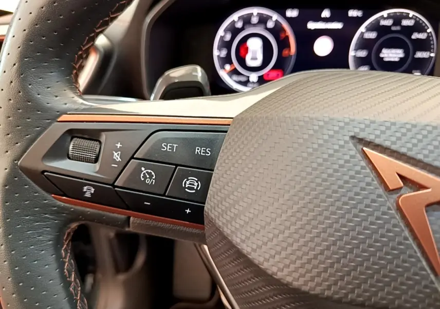 Gros plan sur le volant cuir et alu de la CUPRA Formentor 1.5 TSI 2022, avec commandes multifonctions et logo cuivré.