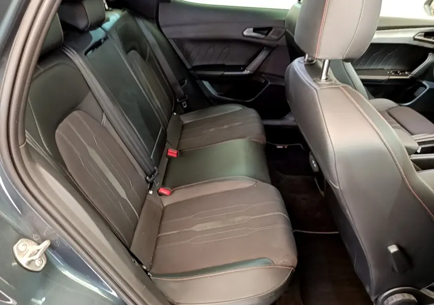 Vue intérieure côté gauche montrant la banquette arrière en cuir noir avec surpiqûres rouges d'une CUPRA Formentor gris foncé.