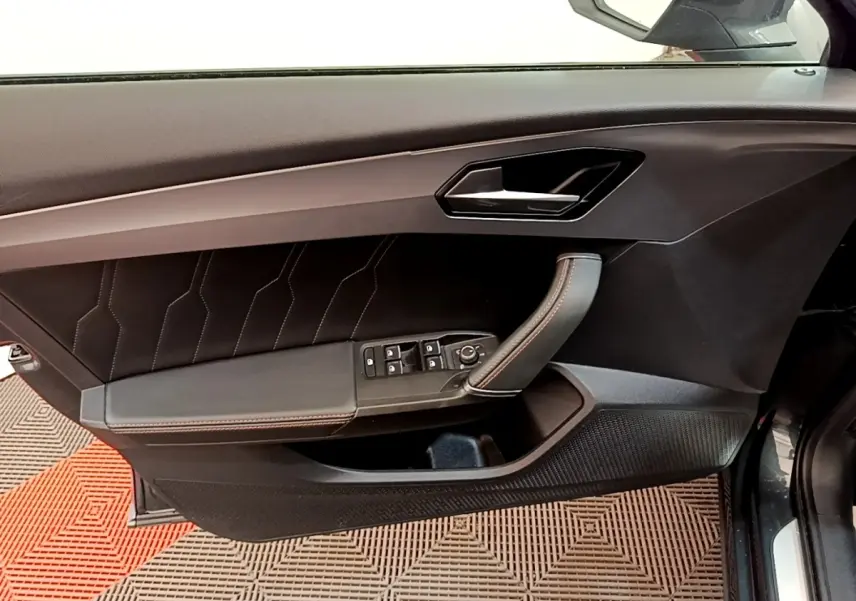 Vue côté gauche sur la porte intérieure noire du CUPRA Formentor 2022 avec surpiqûres rouges et commandes électriques.