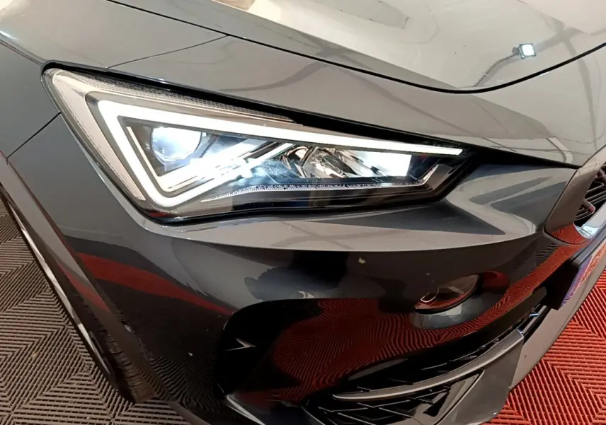 Gros plan sur le phare avant gauche du CUPRA Formentor gris foncé, mettant en valeur son design LED anguleux.