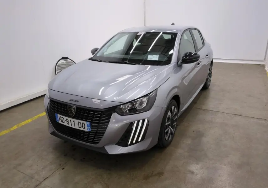Peugeot 208 gris clair vue 3/4 avant droit avec calandre noire et feux LED signature 3 griffes.