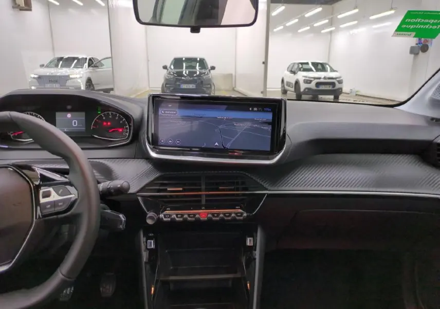 Vue intérieure avant du tableau de bord de la Peugeot 208 gris clair avec écran tactile 10 pouces et volant compact cuir.