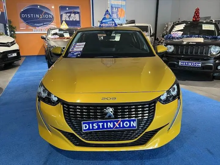 Peugeot 208 jaune Faro métal vue de face en intérieur, avec calandre noire et logo lion distinctif.