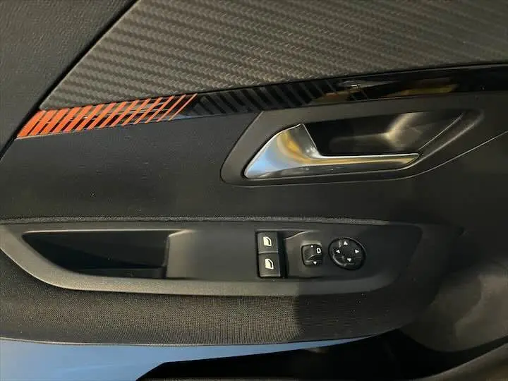 Gros plan sur la porte intérieure côté gauche d'une Peugeot 208 jaune Faro Metal, avec commandes de vitres et poignée argentée.