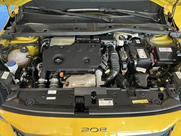 Moteur diesel de la Peugeot 208 jaune Faro Metal vu de dessus avec capot ouvert, montrant les composants propres et bien rangés.