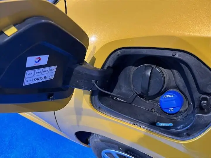 Bouchon de réservoir diesel et AdBlue ouvert sur le côté gauche d'une Peugeot 208 jaune Faro Metal.
