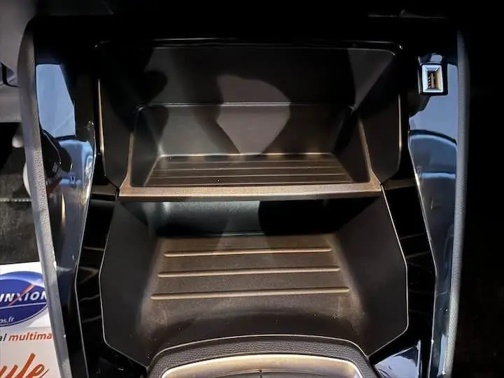 Rangement central avec prise USB visible sur la console d'une Peugeot 208 1.5 BlueHDi jaune Faro Metal, vue de dessus.