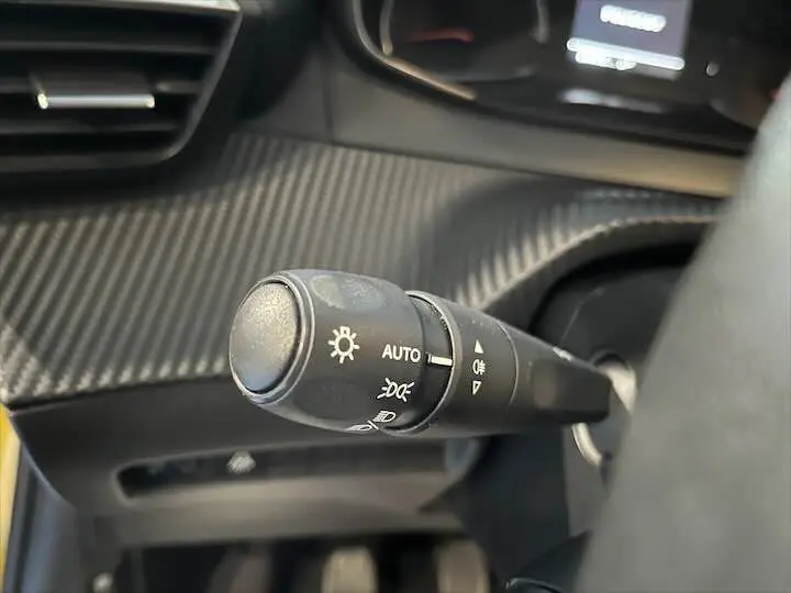 Gros plan sur la commande d’éclairage du tableau de bord d’une Peugeot 208 jaune Faro Metal, finition Active pack.