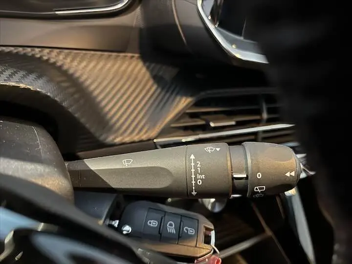 Gros plan sur la commande d'essuie-glace du tableau de bord intérieur d'une Peugeot 208 jaune Faro Metal de 2020.