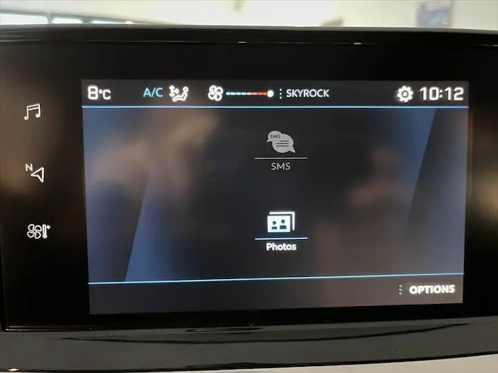 Écran tactile central du tableau de bord du Peugeot 208 2020 affichant les options SMS et Photos en mode multimédia.