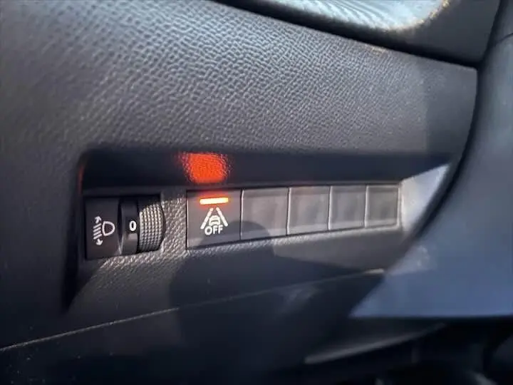 Gros plan sur les commandes du tableau de bord de la Peugeot 208 diesel, voyant d'assistance à la conduite désactivé allumé.