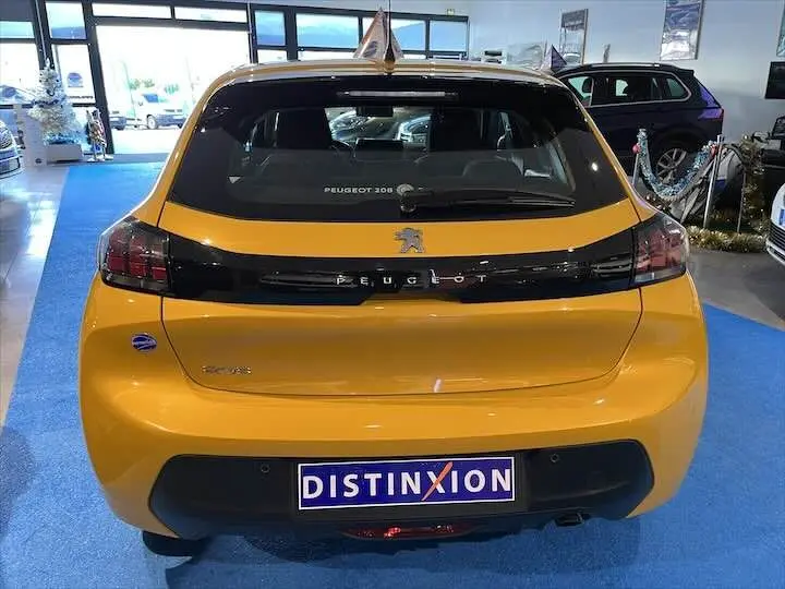 Vue arrière d'une Peugeot 208 jaune Faro Metal exposée en showroom avec logo et plaque Distinxion visibles.