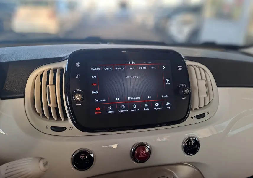 Tableau de bord blanc de FIAT 500 2023 avec écran tactile central affichant la radio FM à 90,7 MHz.