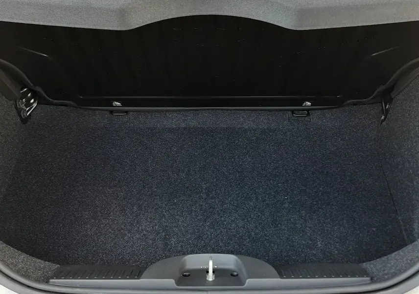 Coffre ouvert vu de dessus d'une FIAT 500 blanche, montrant l'espace de chargement vide et la moquette sombre.