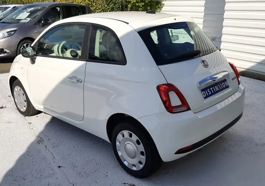 Vue 3/4 arrière droite d'une Fiat 500 blanche 2023 avec jantes acier et logo Distinxion sur le coffre.