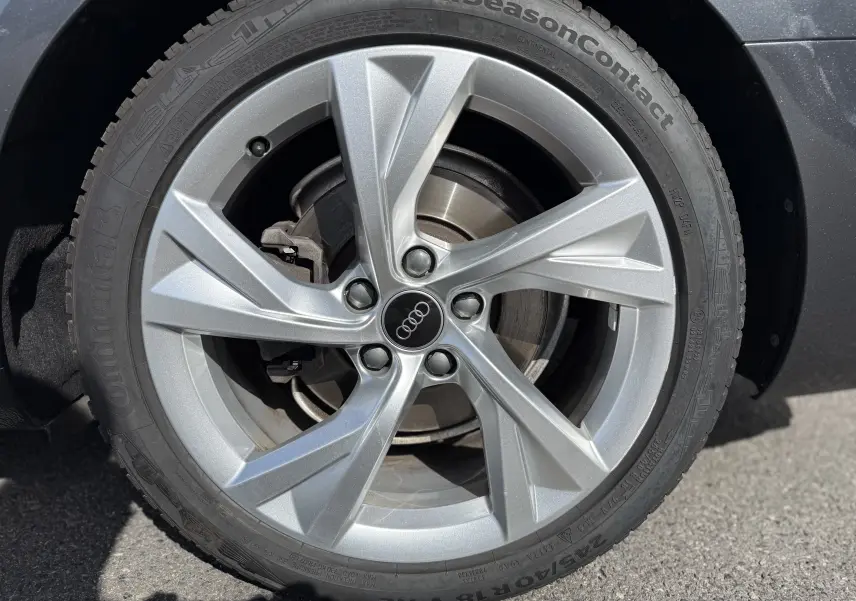 Gros plan sur la jante alliage argentée Audi à 5 branches du pneu Continental AllSeasonContact d'une A4 Avant gris Daytona.
