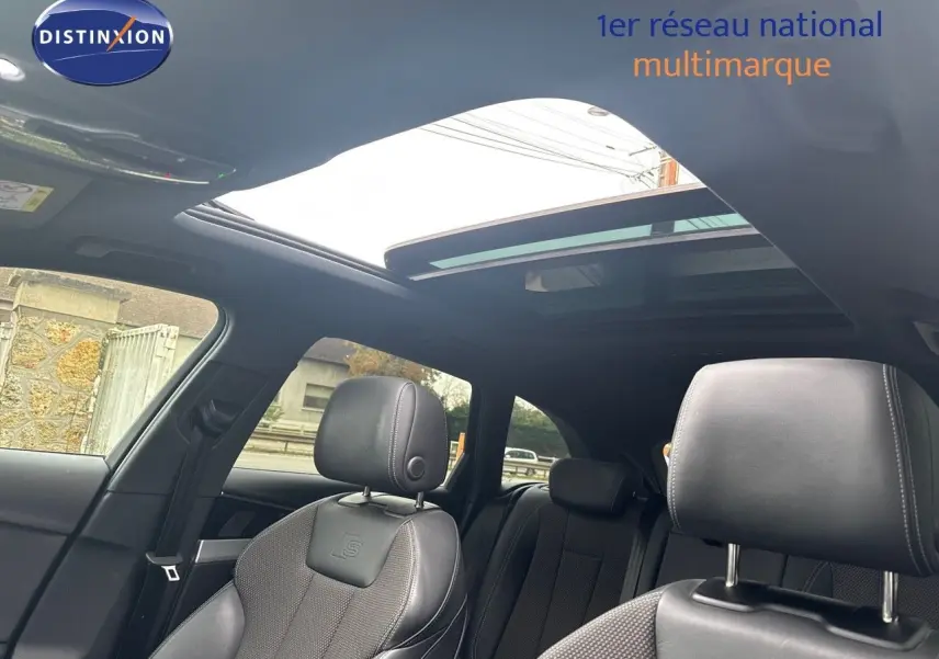 Vue intérieure de l'Audi A4 Avant 35 TDI S-Line 2023, sièges cuir noir avec logo S et toit ouvrant panoramique.