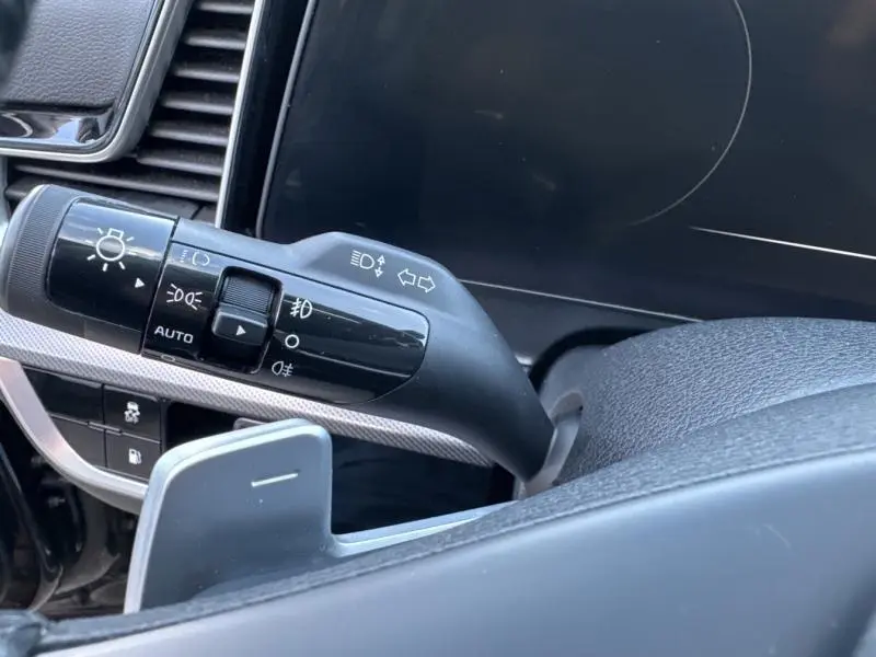 Gros plan sur la commande des phares et clignotants côté gauche du tableau de bord noir du Kia Sportage 2022.