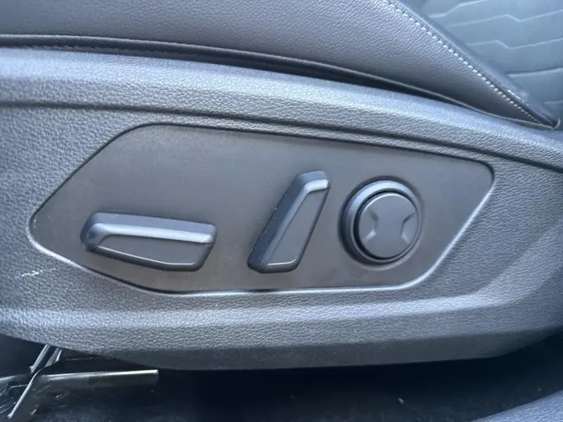 Gros plan sur les commandes électriques de réglage du siège avant noir du Kia Sportage 1.6 T-GDi PHEV 2022.