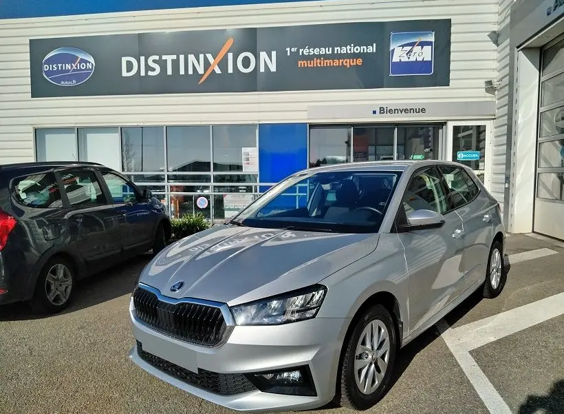 Vue 3/4 avant droite d'une Skoda Fabia blanche 2023, stationnée devant un concessionnaire Distinxion.