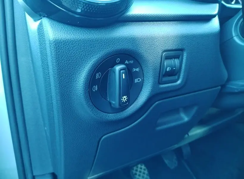 Gros plan sur le tableau de bord noir de la Skoda Fabia 2023 montrant la molette de réglage des phares et l’intensité lumineuse.