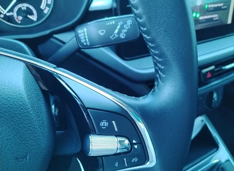 Gros plan sur le volant en cuir noir de la Skoda Fabia 2023, avec commandes intégrées et tableau de bord partiellement visible.