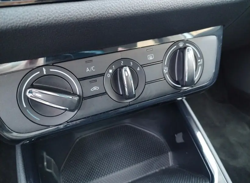 Vue rapprochée des commandes de climatisation noires de la Skoda Fabia 2023, avec réglages manuels et finition brillante.