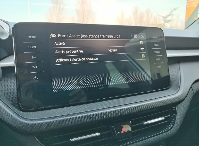 Écran tactile central du tableau de bord de la Skoda Fabia 2023 affichant l'assistance freinage d'urgence Front Assist.