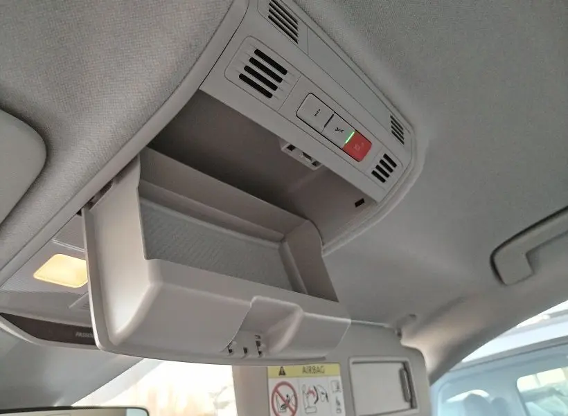 Vue intérieure en plongée sur le rangement de plafond ouvert de la Skoda Fabia blanche 2023, avec éclairage et commandes intégrées.