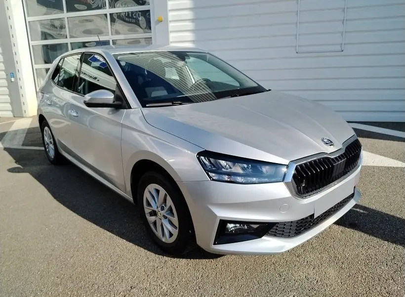 Vue 3/4 avant droite d'une Skoda Fabia blanche 2023 avec calandre noire et phares LED distinctifs.