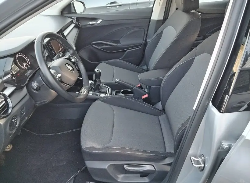 Vue intérieure côté conducteur de la Skoda Fabia blanche 2023, sièges tissu gris et boîte manuelle visible.