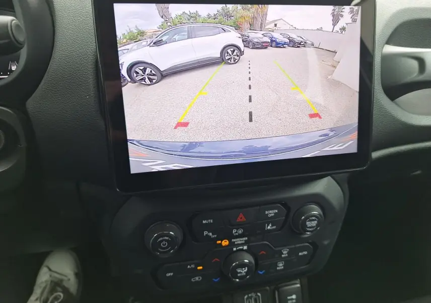 Vue intérieure centrée sur l’écran tactile affichant la caméra de recul d’une Jeep Renegade bleu 2024.
