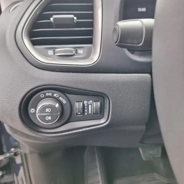 Détail intérieur côté gauche du tableau de bord bleu de la Jeep Renegade 2024 avec commandes des phares et aérateur.