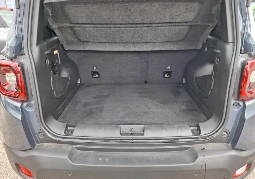 Coffre ouvert d’un Jeep Renegade bleu 2024, vue arrière montrant l’espace de chargement vide et la garniture intérieure.