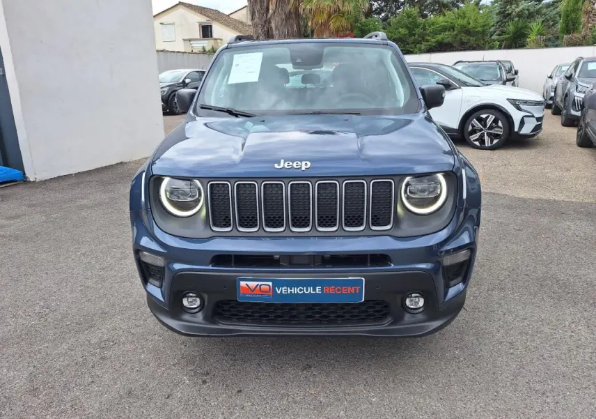 Vue avant d'un Jeep Renegade bleu 2024 avec phares ronds allumés et calandre à sept fentes distinctives.