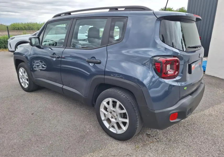 Vue 3/4 arrière droite d'un Jeep Renegade bleu 2024 avec barres de toit et jantes alliage 17 pouces.
