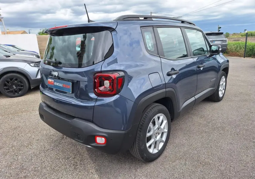 Jeep Renegade bleu vue 3/4 arrière droit, avec barres de toit et jantes alliage 17 pouces visibles.