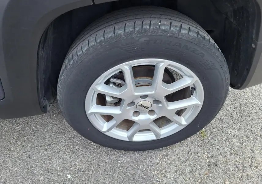 Gros plan sur la roue avant gauche d’un Jeep Renegade bleu 2024 avec jante alliage 17 pouces et logo Jeep au centre.